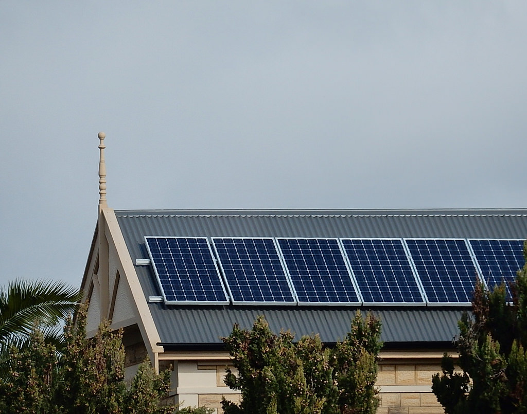 A picture of solar panels on a roof undeneath a cloudy sky